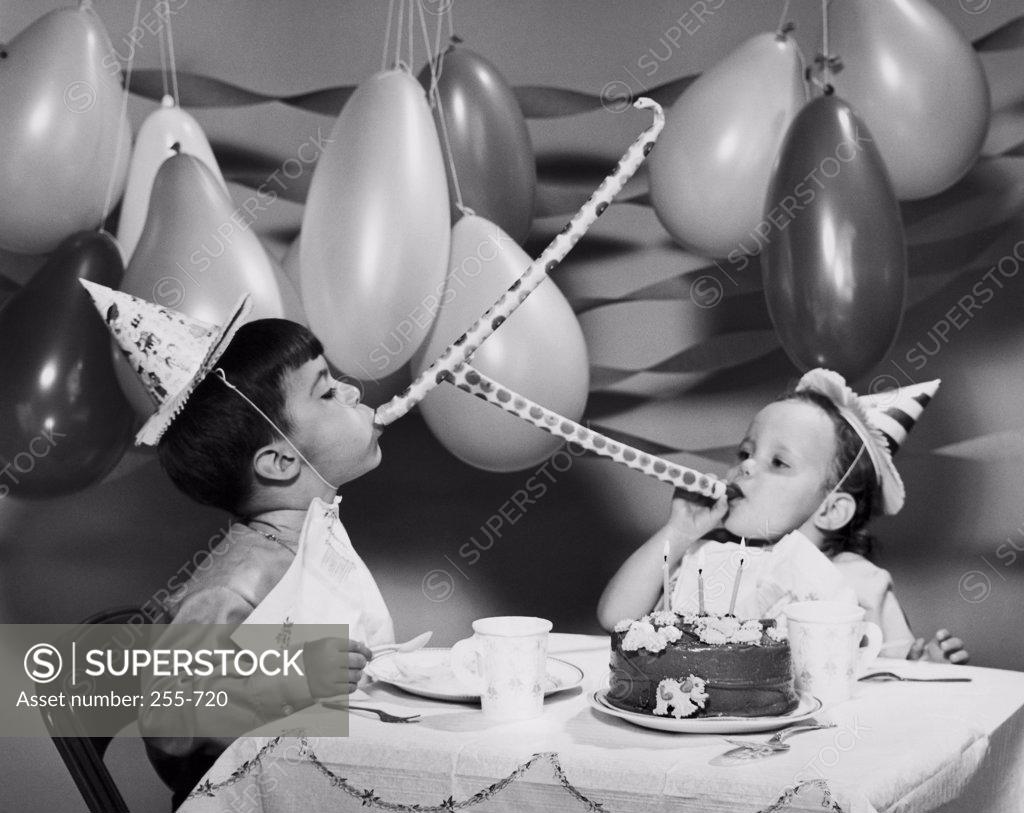 Stock Photo: 255-720 Two boys blowing noisemakers at birthday party