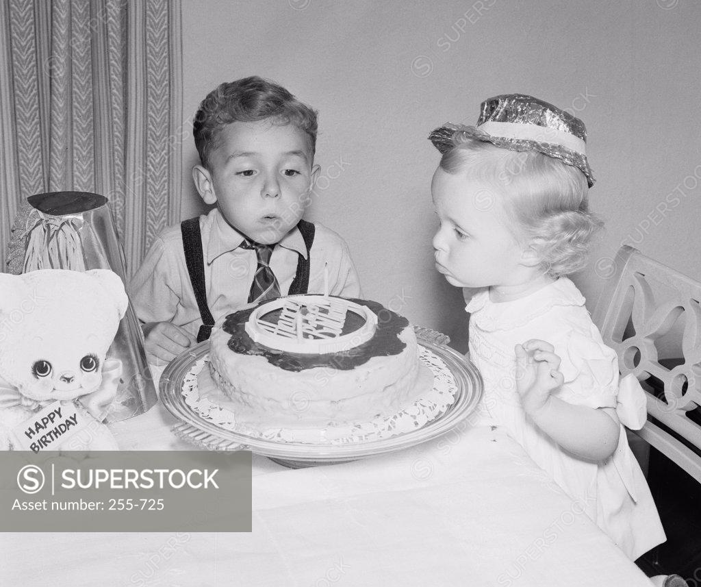 Stock Photo: 255-725 Children blowing candles on birthday cake