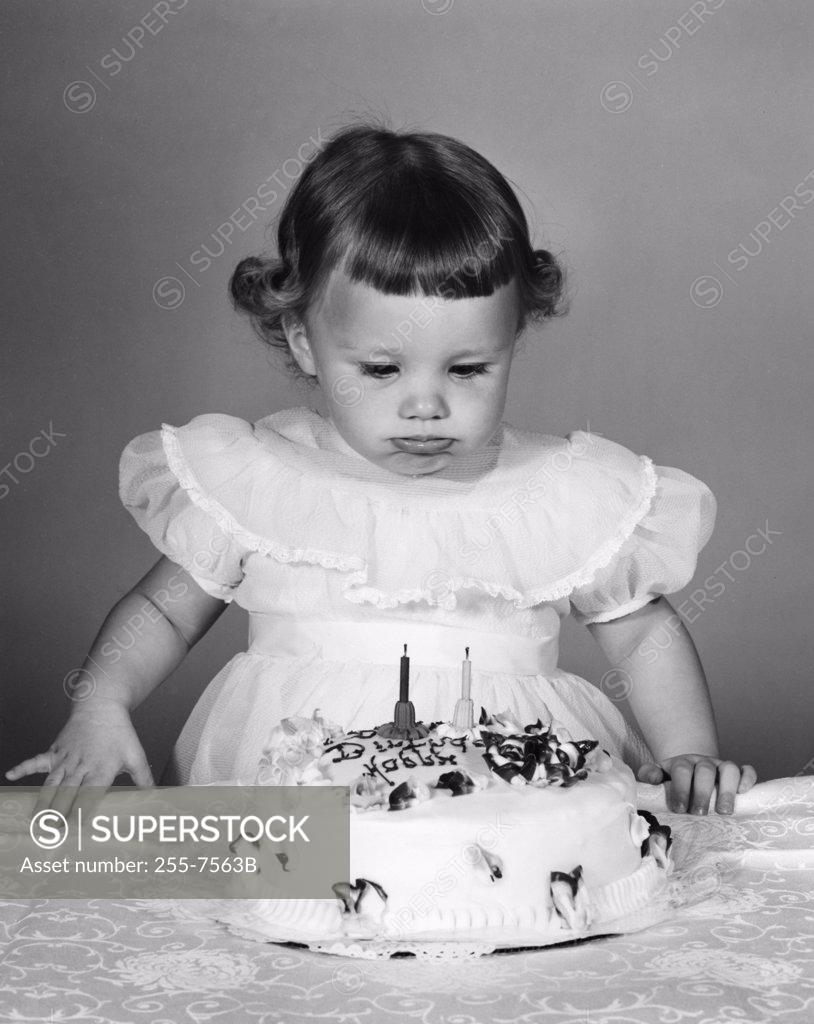 Stock Photo: 255-7563B Girl looking at birthday cake, making a face
