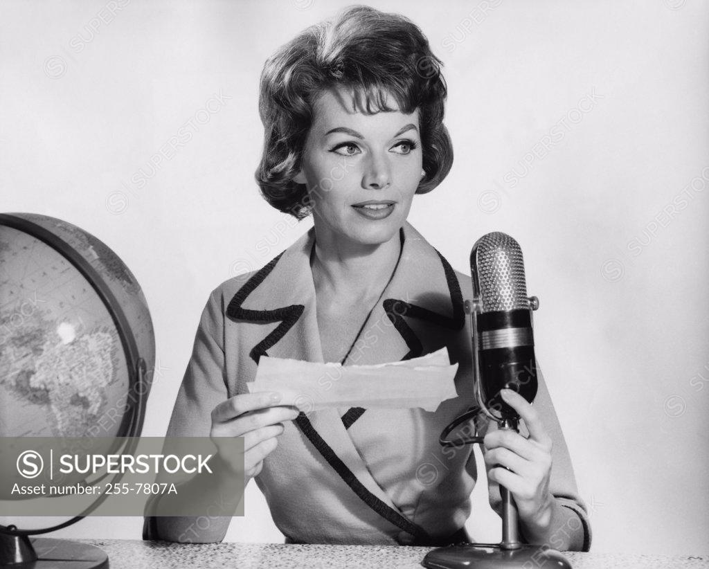 Stock Photo: 255-7807A Mid adult woman reading a report on a microphone