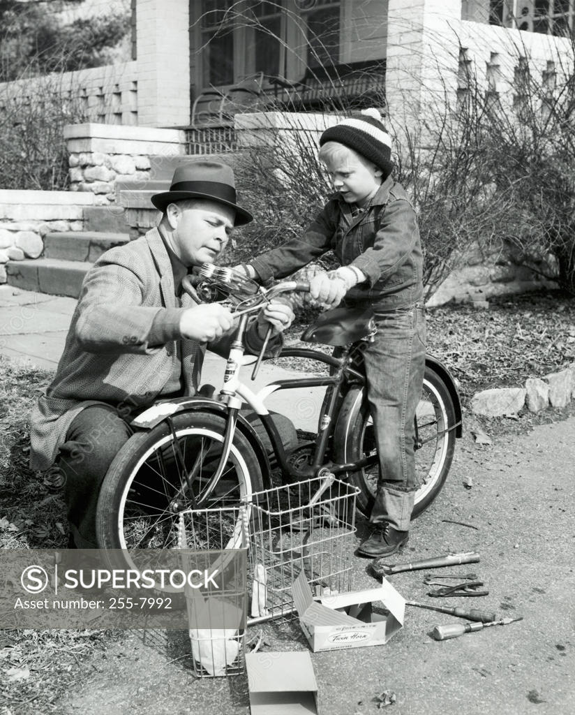 Stock Photo: 255-7992 Close-up of a father repairing a bicycle with his son
