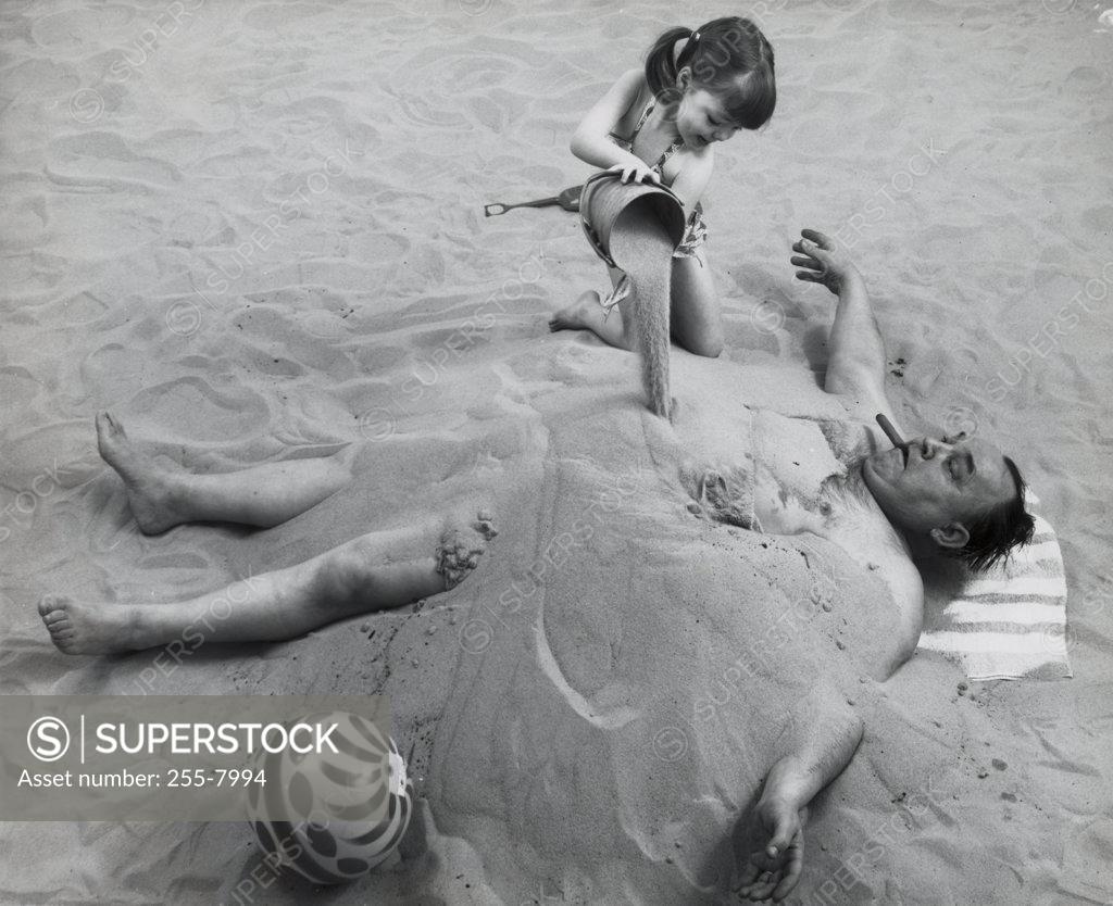 Stock Photo: 255-7994 High angle view of a girl burying her father in sand on the beach