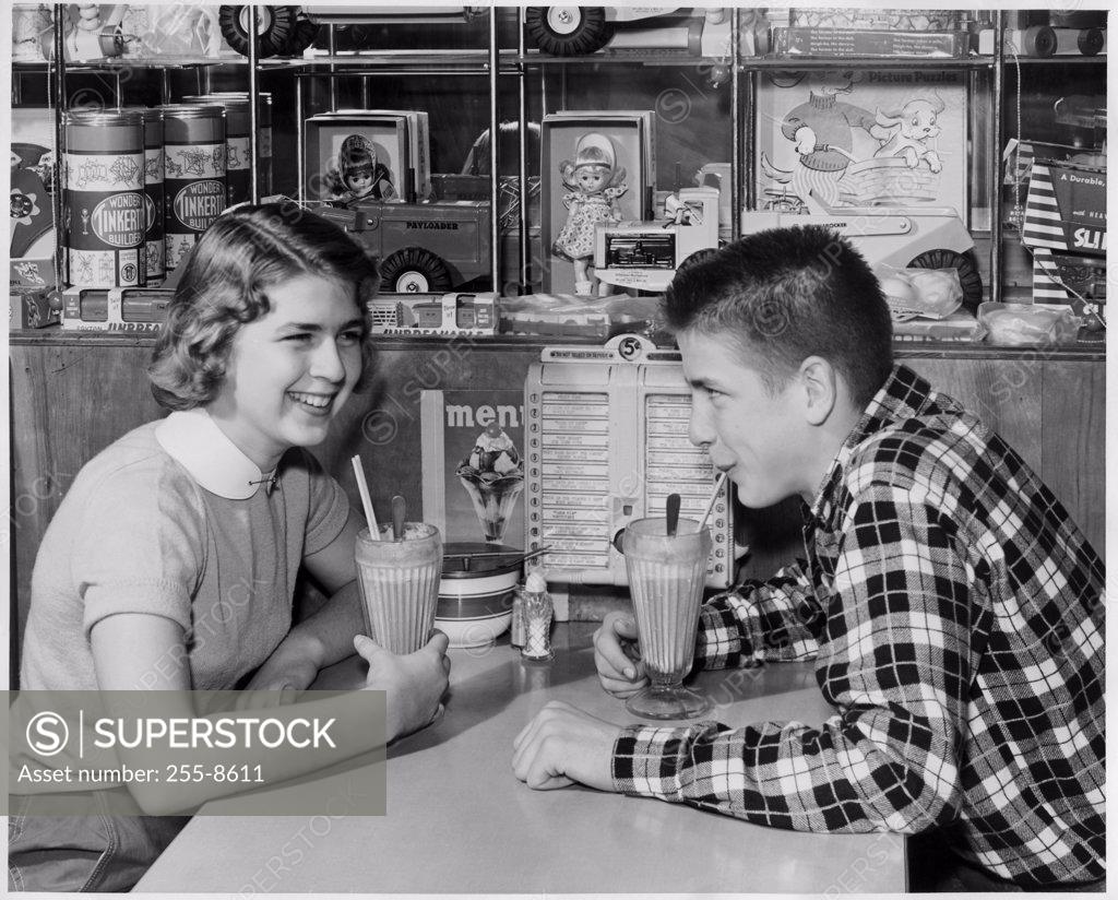 Stock Photo: 255-8611 Side profile of a teenage couple drinking a milk shake in a restaurant
