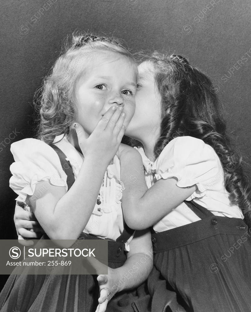 Stock Photo: 255-869 Girl whispering in her sister's ear