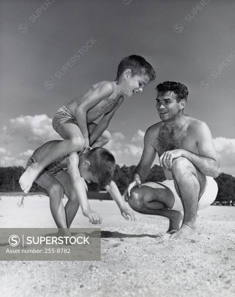 Stock Photo: 255-8782 Father watching boys playing on beach
