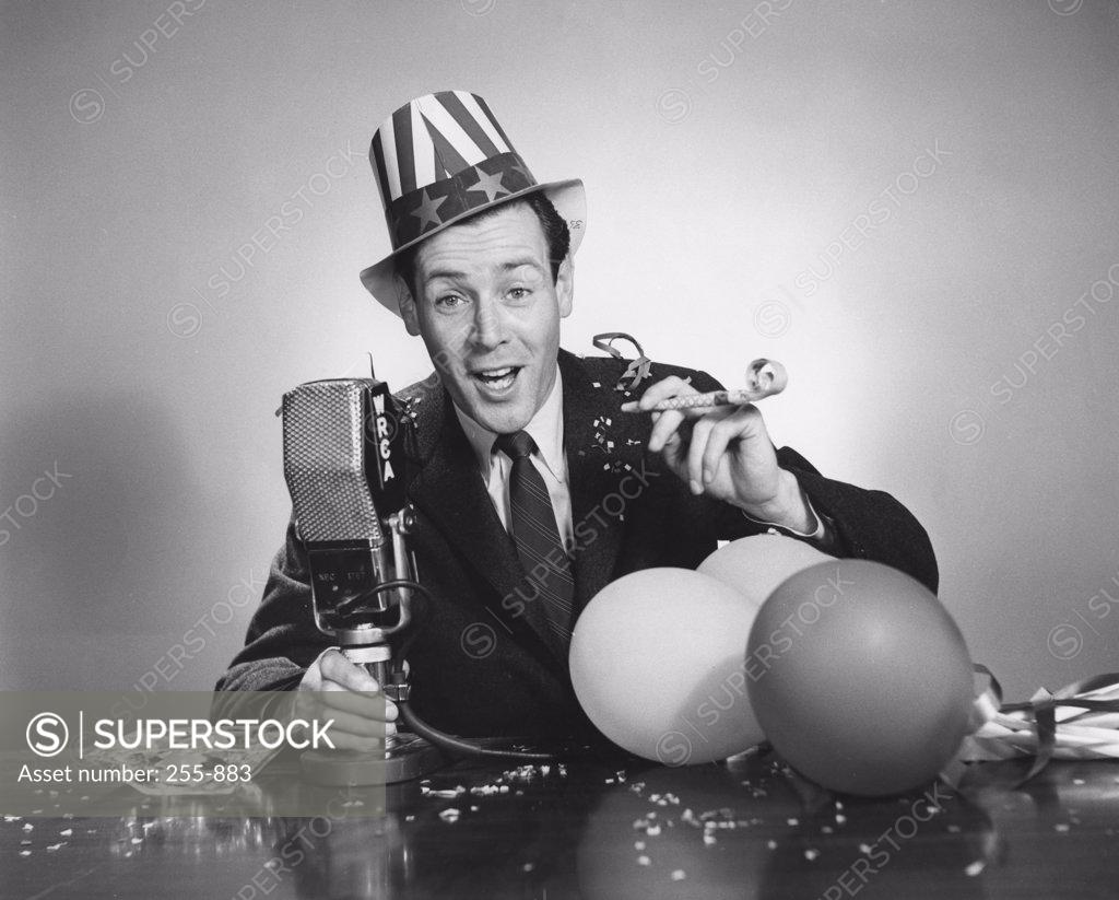 Stock Photo: 255-883 Studio portrait of man with microphone and party blower