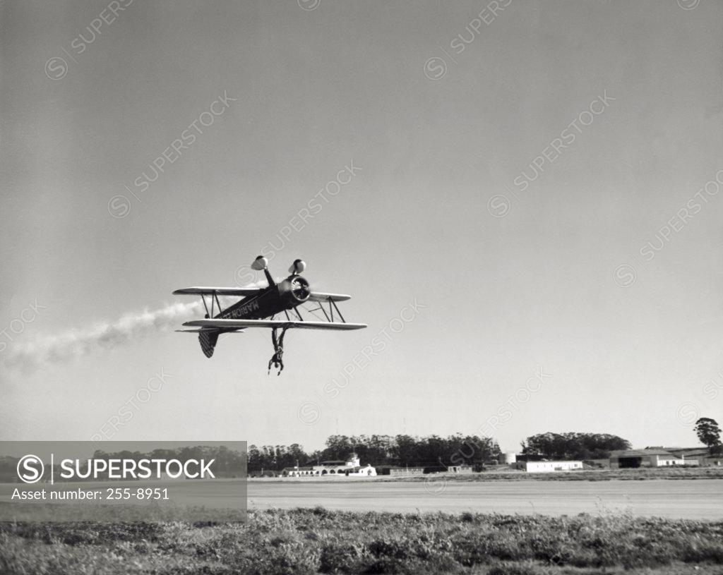 Stock Photo: 255-8951 Low angle view of an aircraft upside down in flight with wing walker