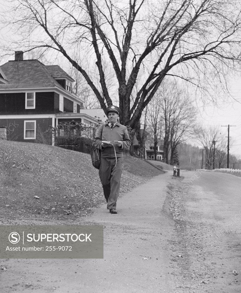Stock Photo: 255-9072 Postman walking with his mail bag