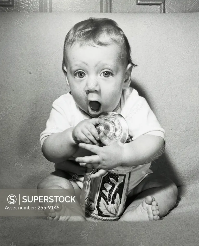 Portrait of a baby boy holding a jar