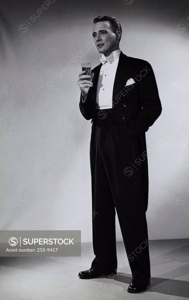 Stock Photo: 255-9417 Young man standing and holding a glass