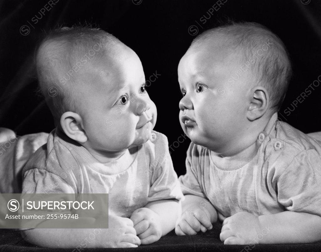 Stock Photo: 255-9574B Two babies leaning on elbows and looking at each ether