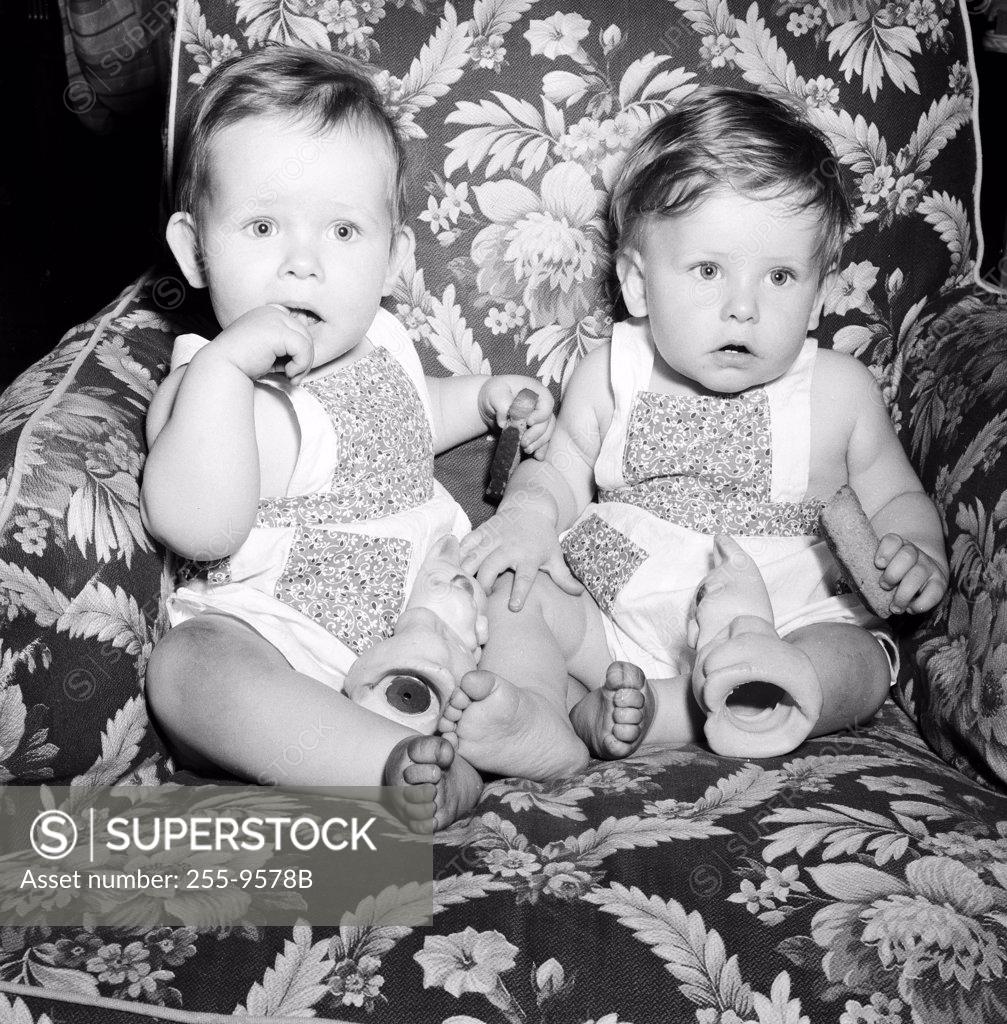 Stock Photo: 255-9578B Two baby girls sitting on armchair and playing with rubber toys