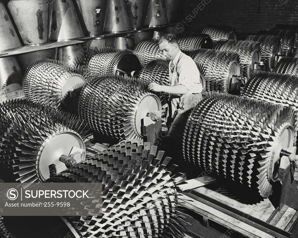 Stock Photo: 255-9598 Manual worker working on compressor rotors in a jet engine factory