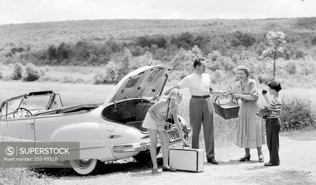 Stock Photo: 255-9921B Parents and their children loading luggage into a car