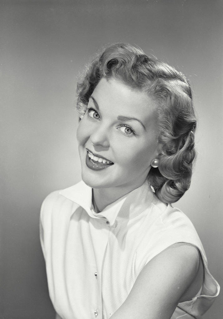 Portrait of a young woman in sleeveless shirt smiling looking at camera.