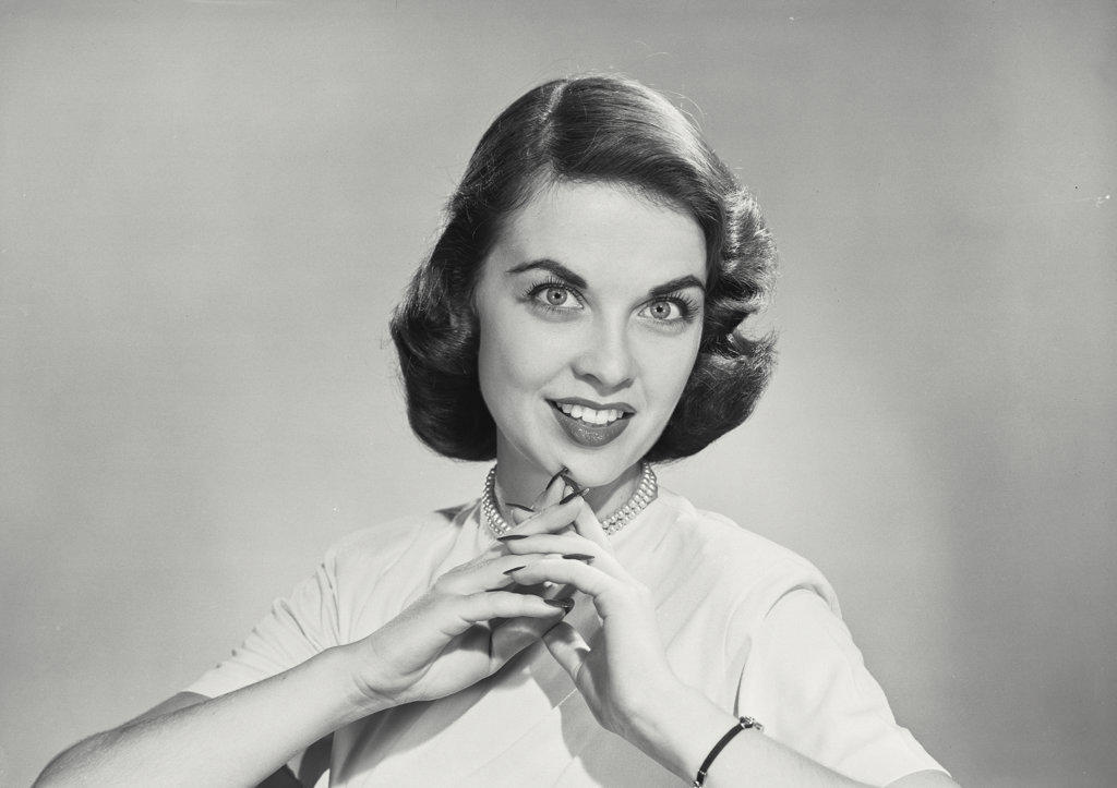 Brunette woman with hands clasped in front of chin