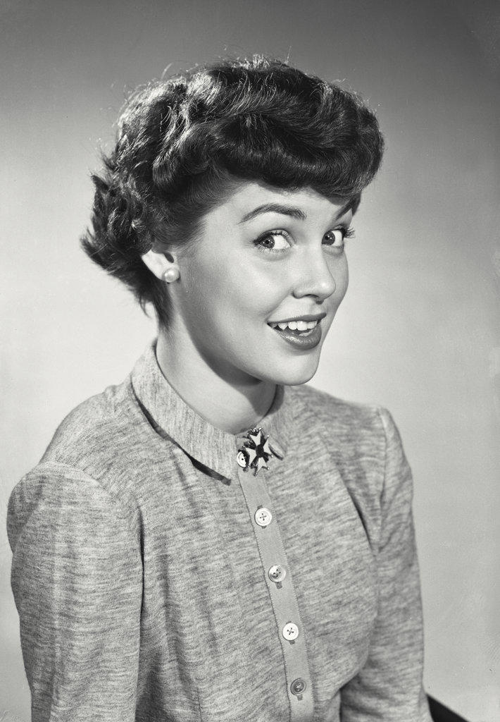 Woman with short dark hair wearing button up blouse and brooch