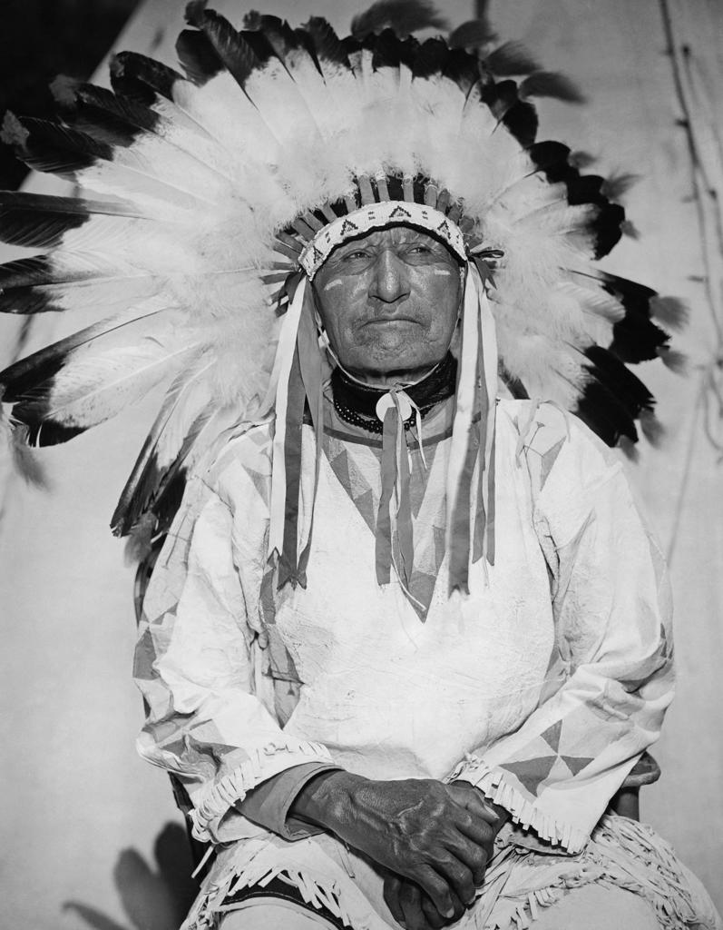 American Horse sitting and wearing a headdress