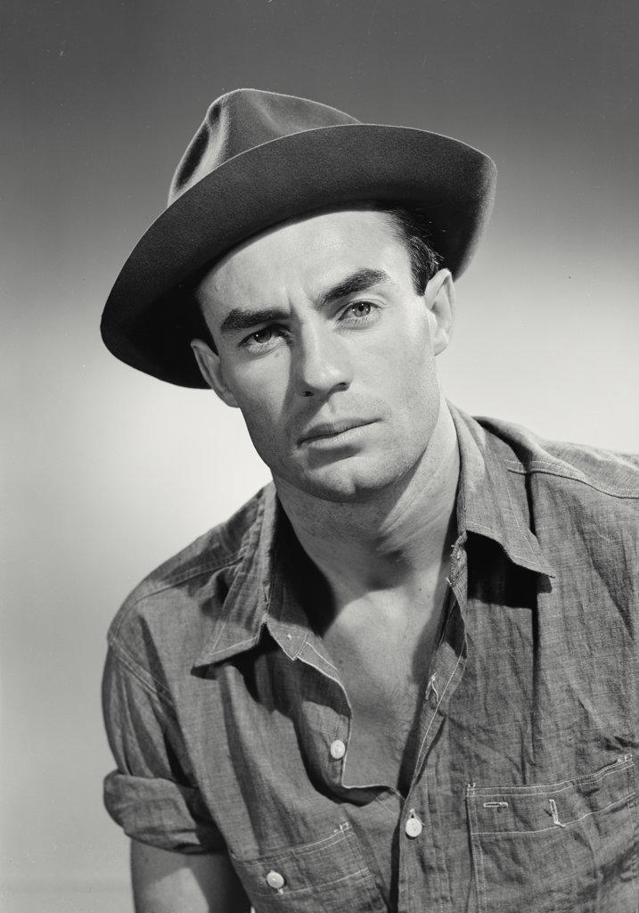 Portrait of man in button shirt and hat smiling.