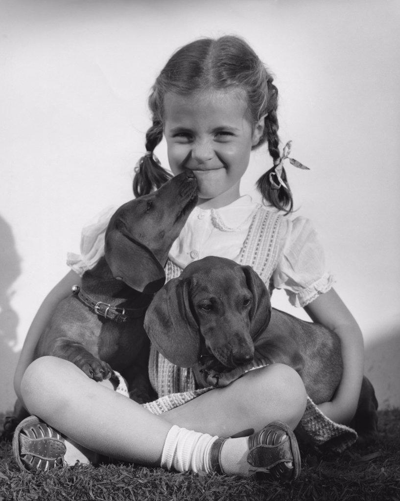 Close-up of a girl sitting and holding two Dachshund puppies