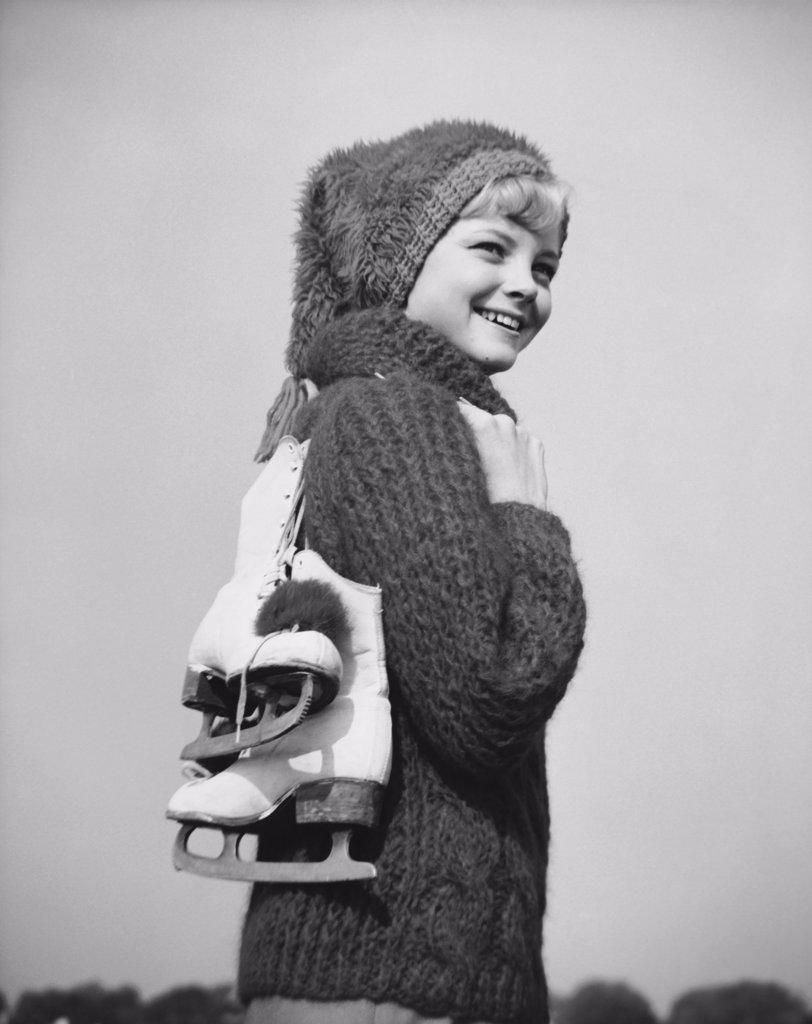 Teenage girl carrying ski boots and smiling