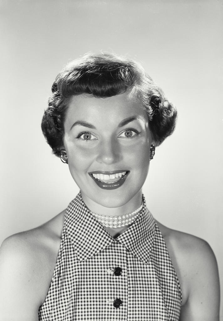 Portrait of brunette woman smiling wearing pearl necklace and sleeveless blouse