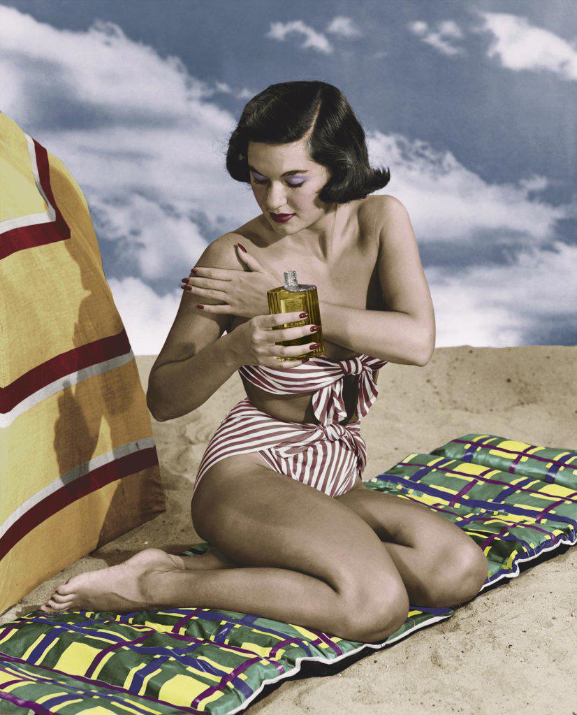 Young woman applying suntan lotion on beach