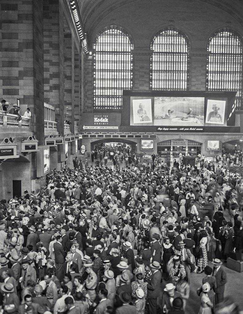 View looking at Kodak Exhibit sign behind crowd of people at a busy Grand Central Station.