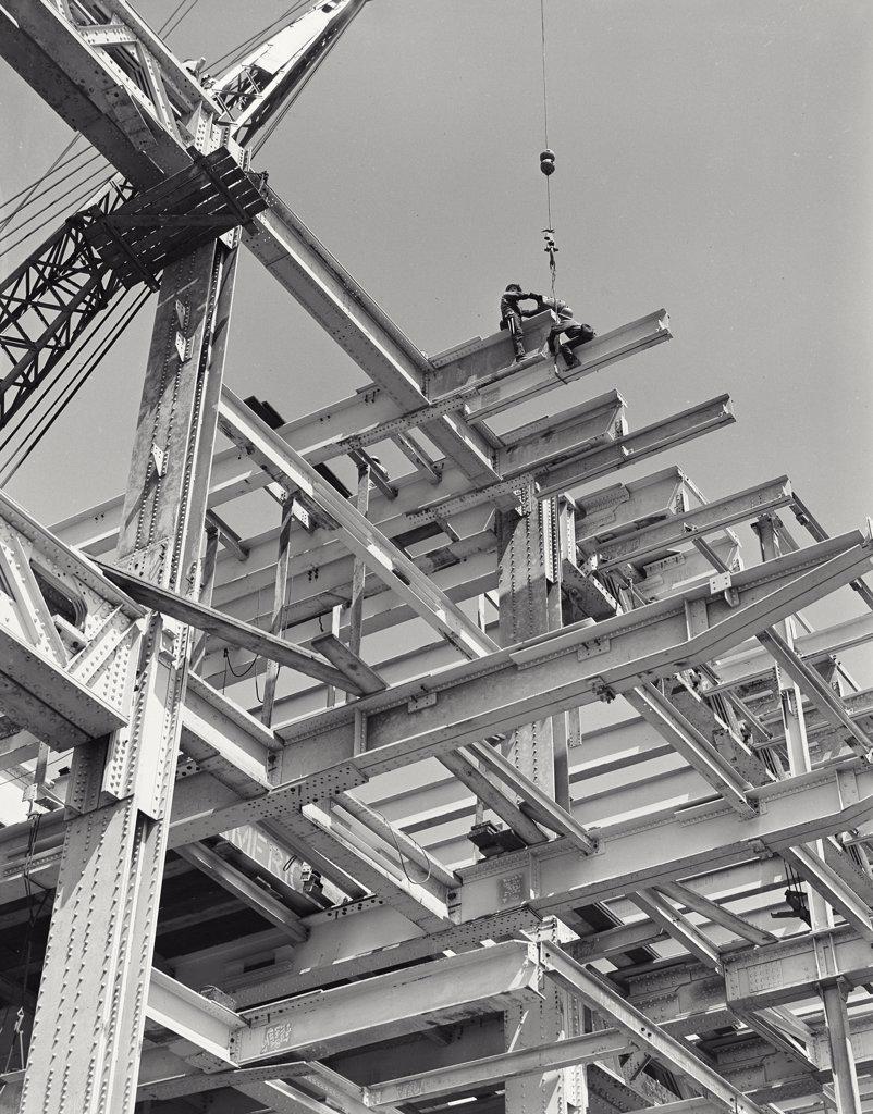 View looking up at men sitting on steel girders on a construction site near the United Nations Building, New York City