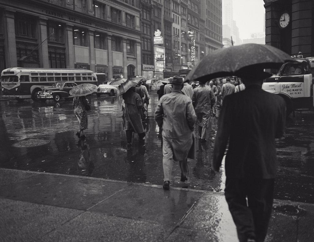 Looking west on 42nd Street, people with umbrellas on busy Madison Avenue in Manhattan in the rain
