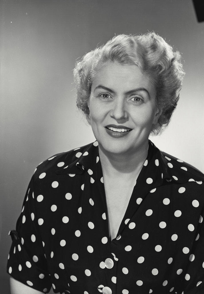 woman in polka dot shirt smiling at camera.