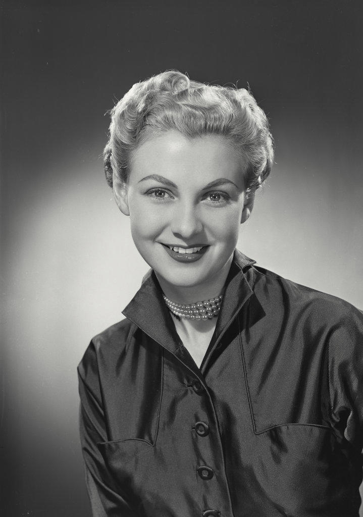 woman with short hair in button shirt smiling at camera