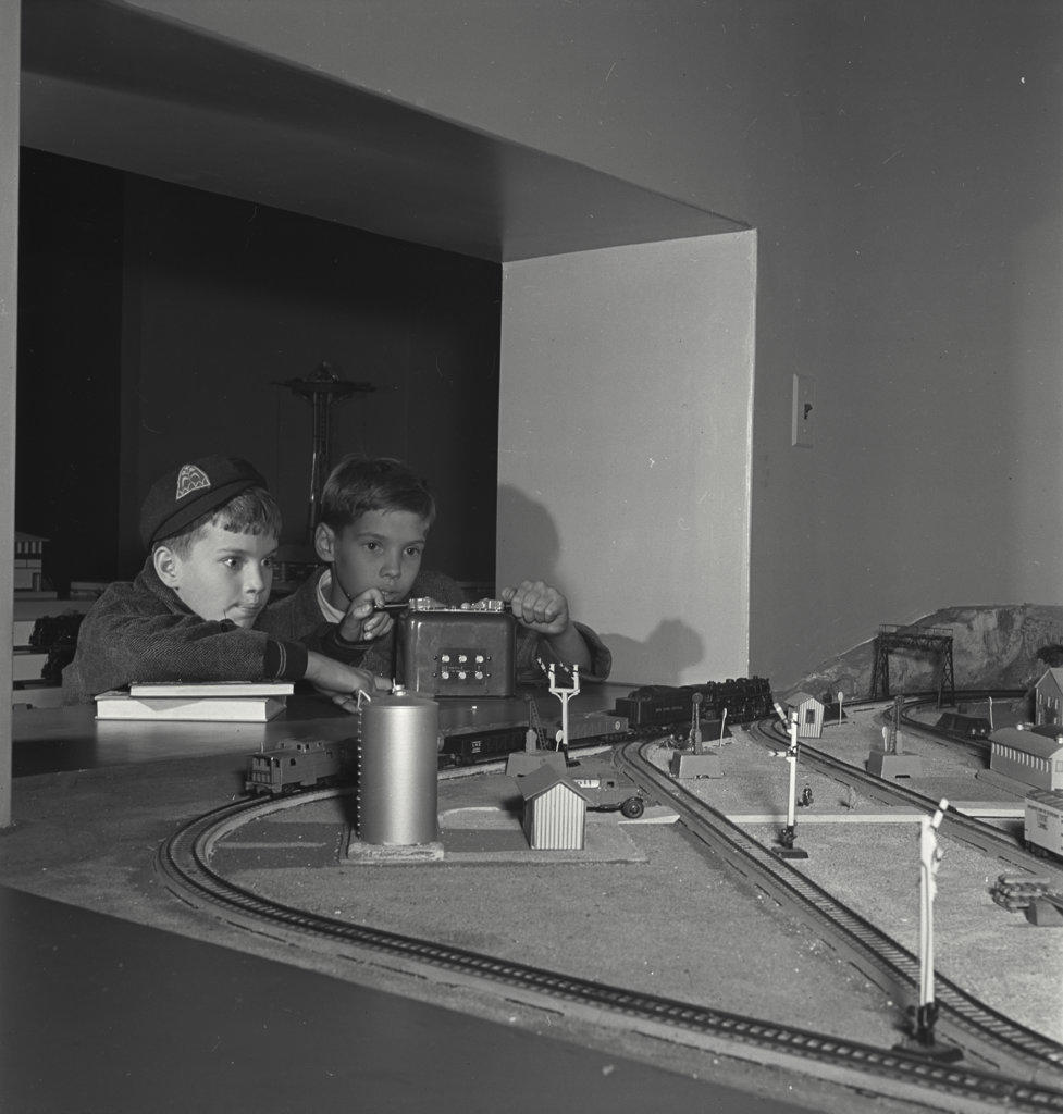 Two young boys playing with model train set