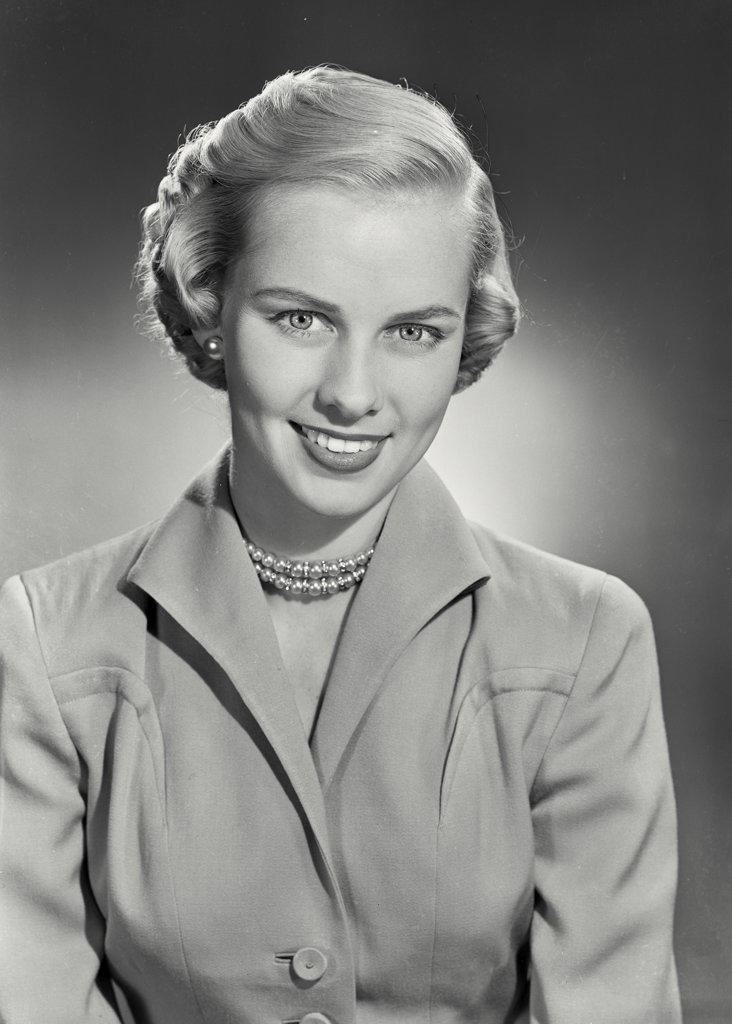 woman with short hair in coat smiling at camera.