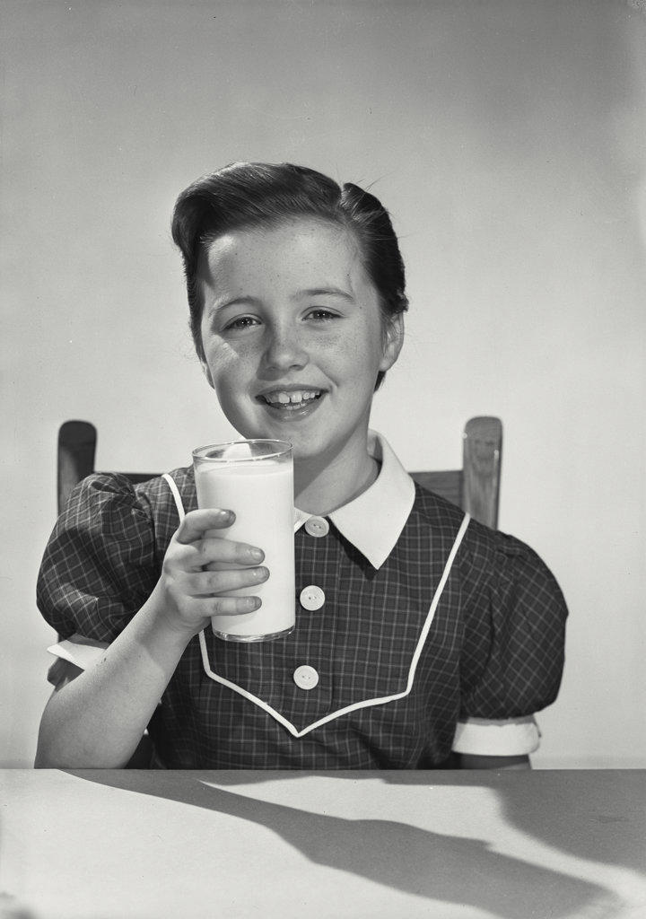 young girl in dress holding glass of milk