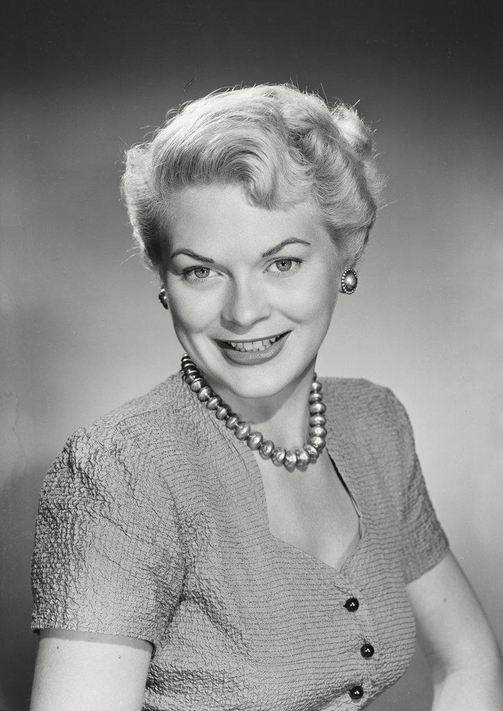 Portrait of smiling woman with blonde hair wearing necklace and button up blouse