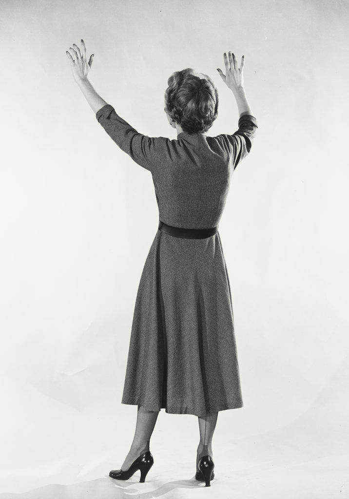 Back of woman in button dress smiling off camera with hands up