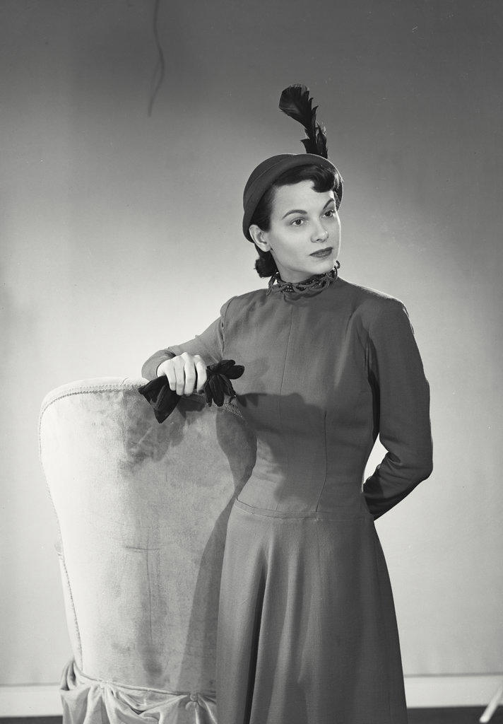 Fashionable woman leaning on high backed chair