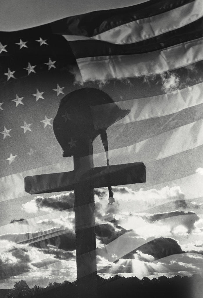 Helmet on cross with clouds in background and American Flag