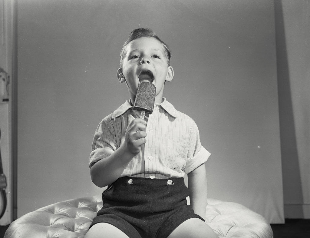 Little boy licking ice cream pop.