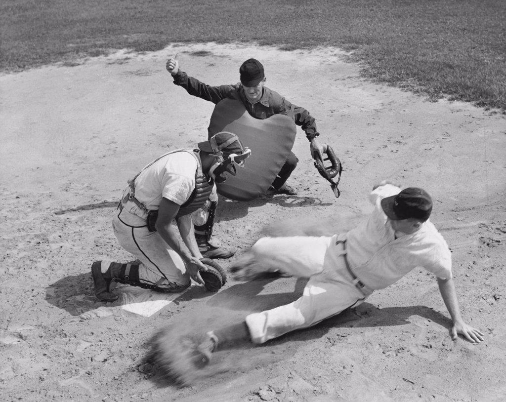 High angle view of a baseball player sliding on home base and a catcher trying to tag him