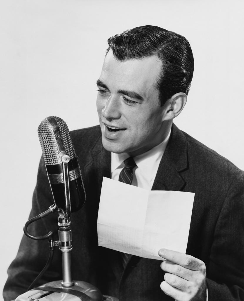 Mid adult man speaking into a microphone