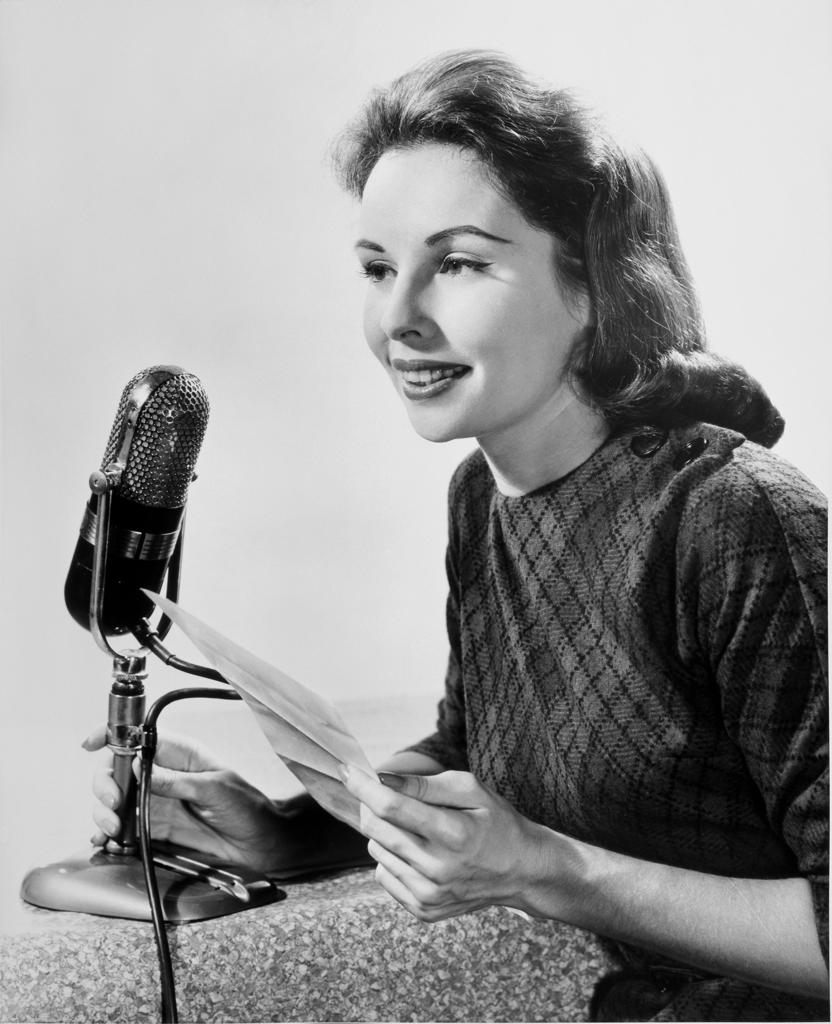 Mid adult woman speaking into a microphone
