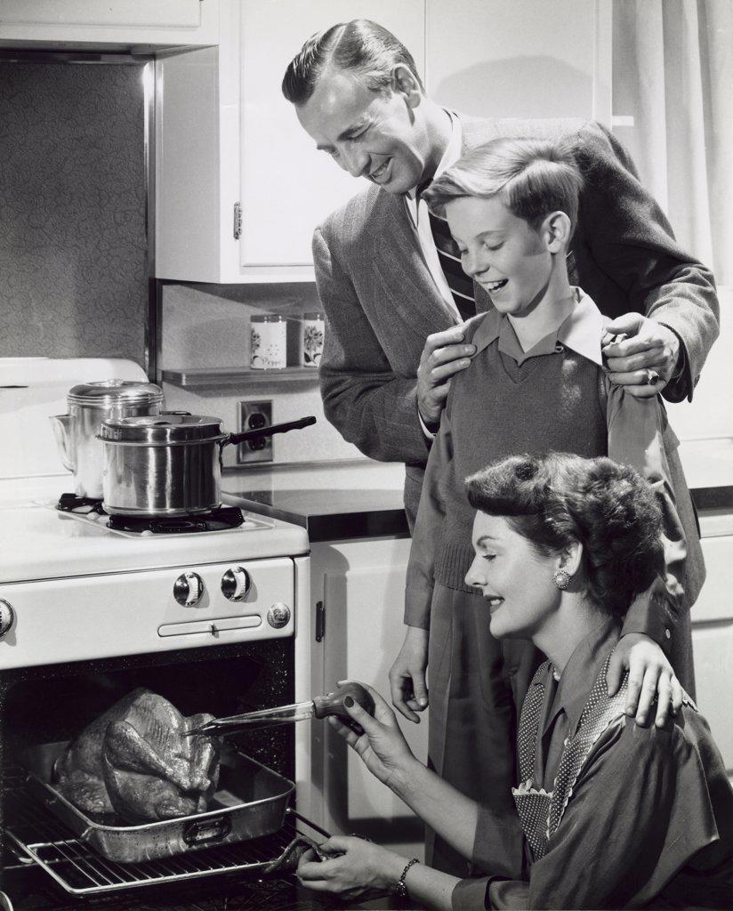 Parents and their son preparing a turkey in the kitchen