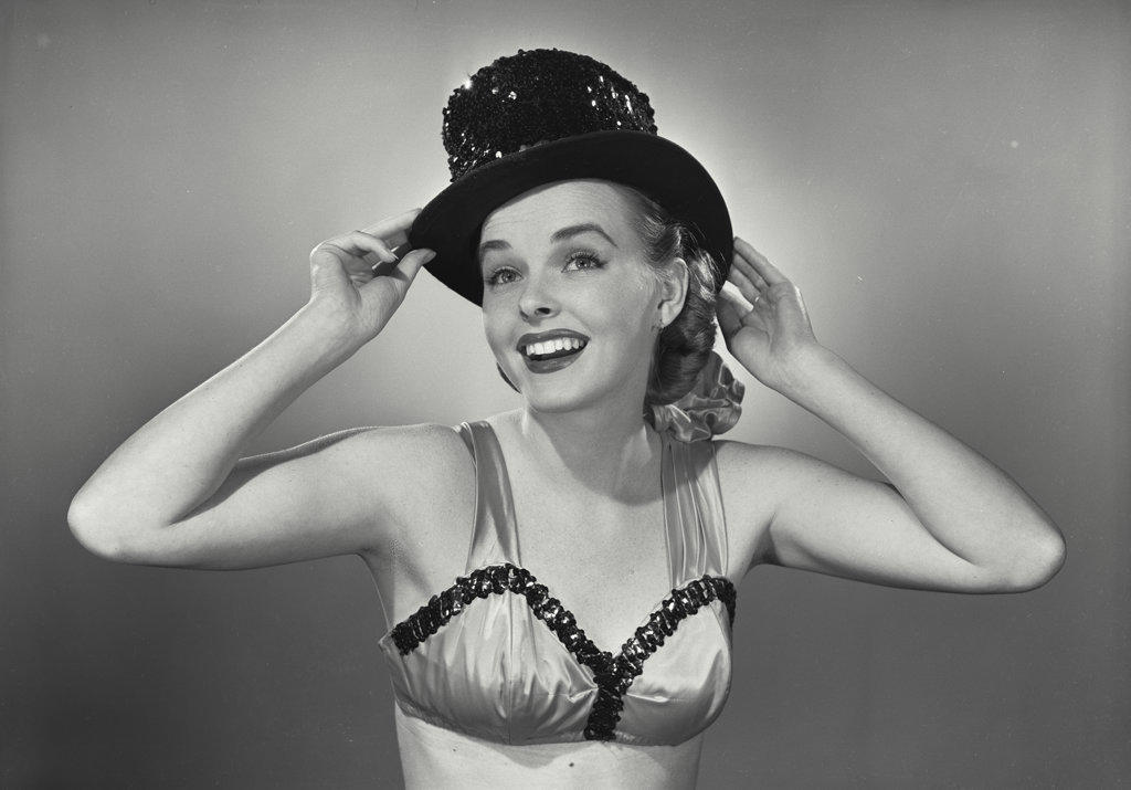 Young woman smiling in bra and top hat