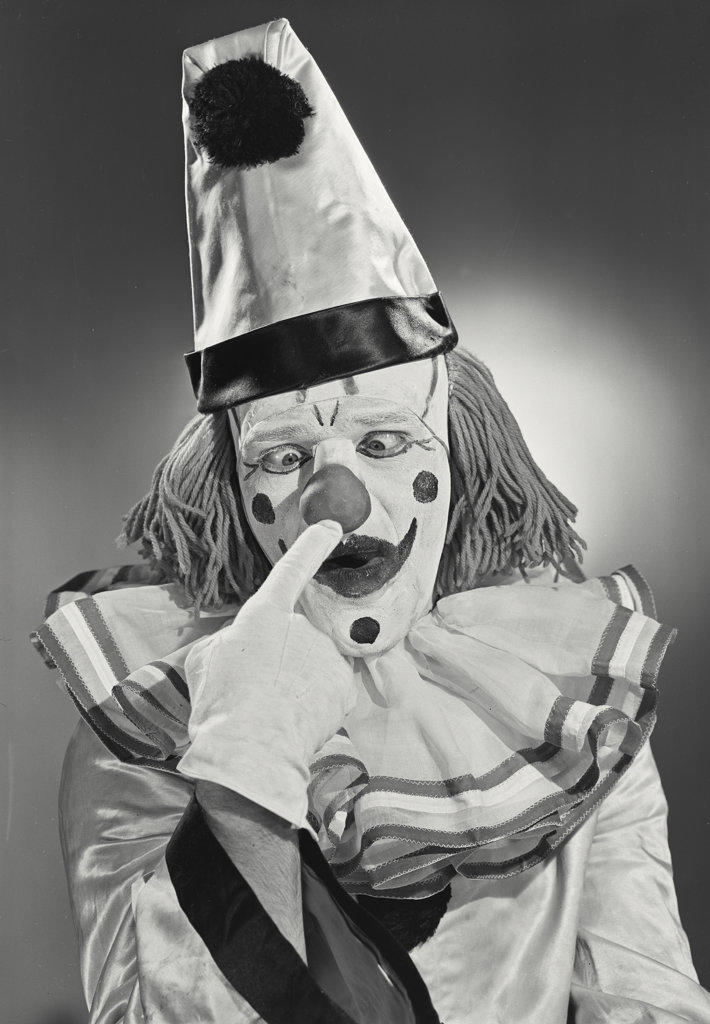 Portrait of clown wearing silly hat poking nose