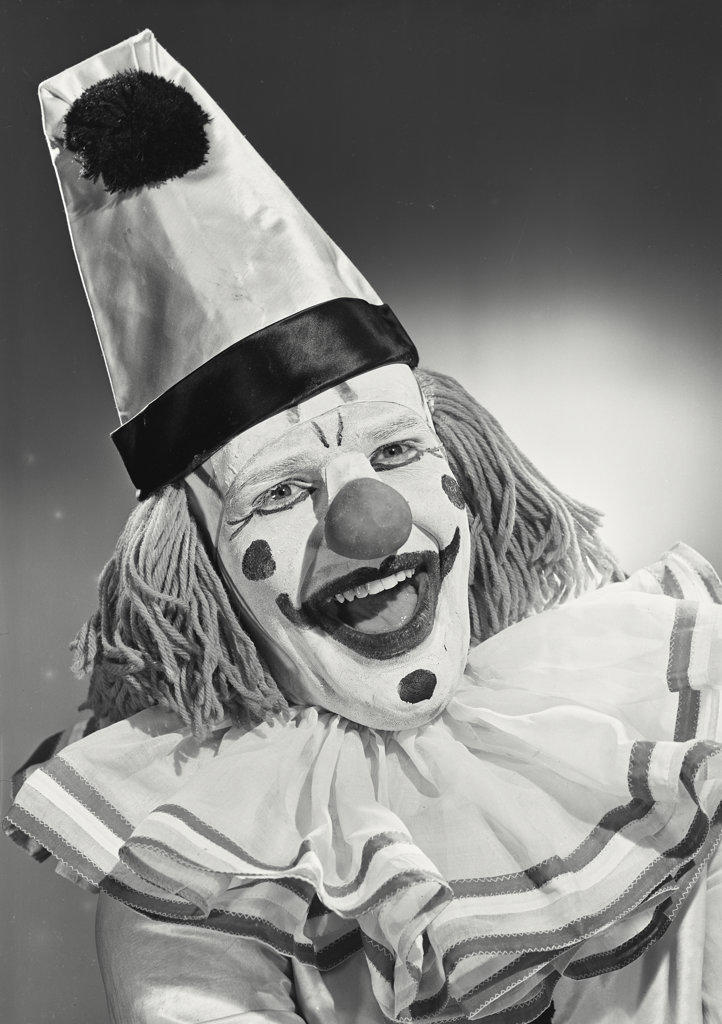 Portrait of clown wearing silly hat and smiling wide.