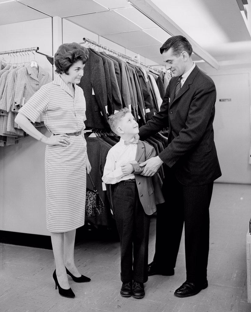 Parents assisting son trying on suit in shop