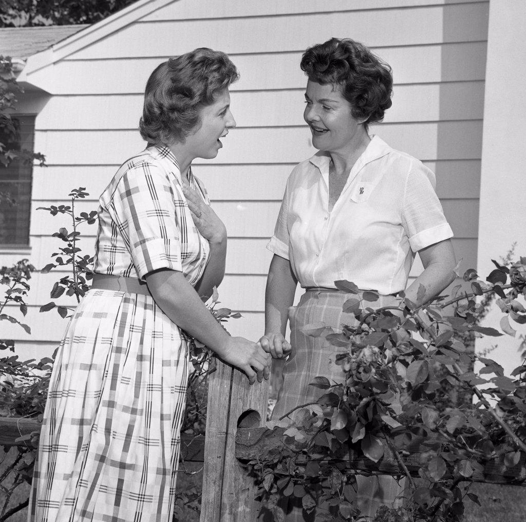 Two women talking over garden fence