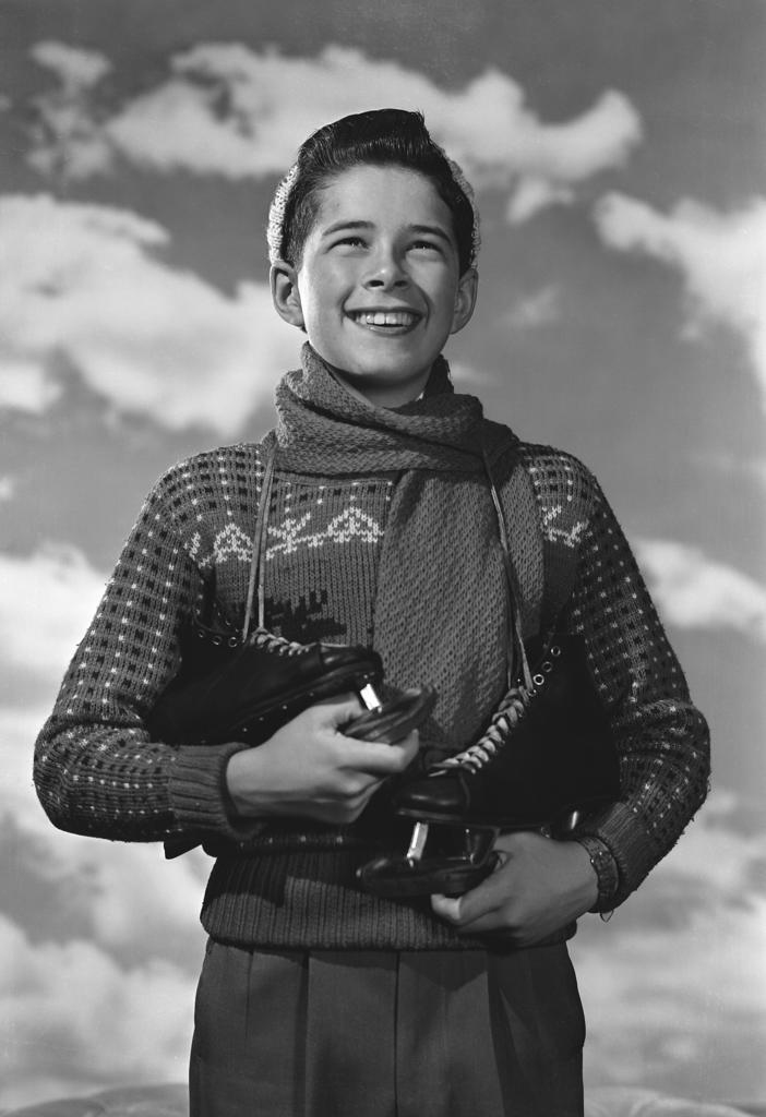 Boy with ice-skates looking away and smiling